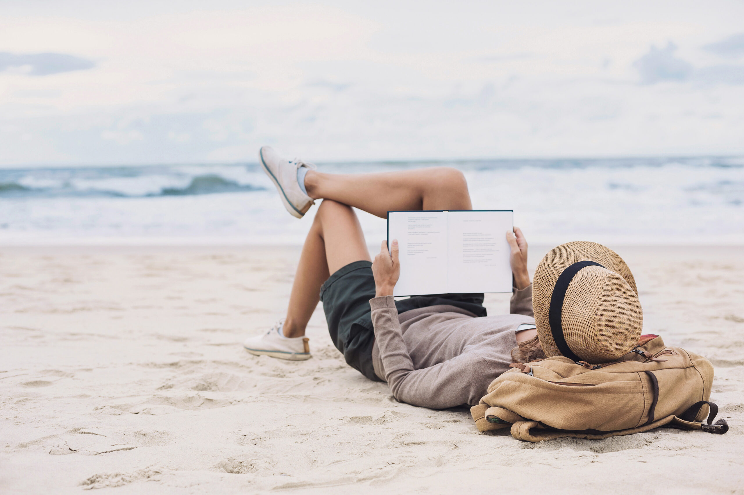 Young woman reading a book on the beach. Relaxation resting vacations concept